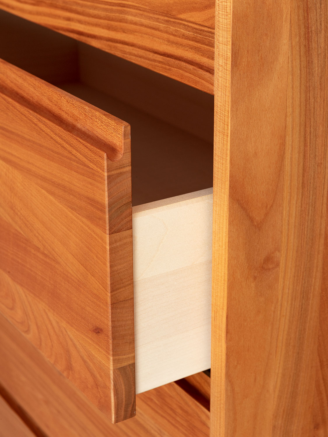 Massivholzkommode in Kirschbaum. Detail der optionalen Grifffräsung sowie der Schubladzarge in Ahron
