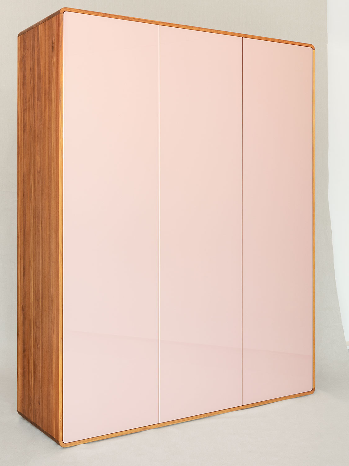 Massivholzschrank "Sfera" aus Nussbaum massiv mit Türen aus farbig lackiertem Glas. Die Nuss wirkt sehr hell, weil sie lange der Sonne ausgesetzt war.