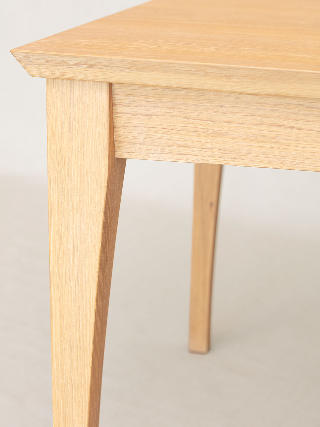 Esstisch Filago, Eckdetail mit geschwungenem Bein und Zarge, Eiche massiv weissge&ouml;lt